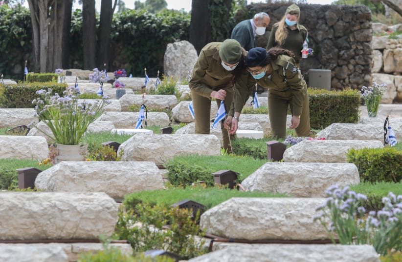 IDF soldiers place Israeli flags on the graves of fallen soldiers at Mount Hertzl ahead of Israel's Memorial Day (photo credit: MARC ISRAEL SELLEM/THE JERUSALEM POST)