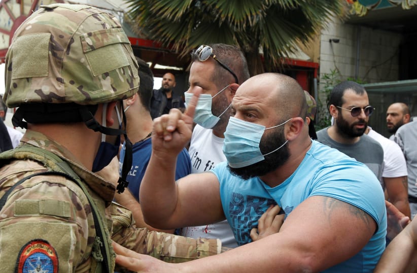 A Lebanese demonstrator gestures to a Lebanese soldier, during a protest against the collapsing Lebanese pound currency and the price hikes, in Zouk, north of Beirut (photo credit: REUTERS/MOHAMED AZAKIR)