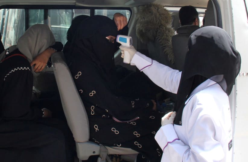 A health worker takes temperature of passengers of a van, amid fear of coronavirus disease (COVID-19), on the outskirts of Taiz, Yemen April 12, 2020. Picture taken April 12, 2020. (photo credit: ANEES MAHYOUB/REUTERS)