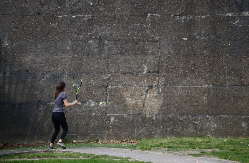 A woman is seen playing tennis with herself, following the outbreak of the coronavirus disease (COVID-19), London, Britain, April 27, 2020 (photo credit: REUTERS/HANNAH MCKAY)