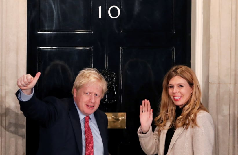 Britain's Prime Minister Boris Johnson and his girlfriend Carrie Symonds gesture as they arrive at 10 Downing Street on the morning after the general election in London, Britain (photo credit: REUTERS/THOMAS MUKOYA)