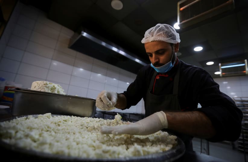 A worker prepares a traditional sweet "Konafa" at a shop, after the government eased the restrictions on movement aimed at containing the spread of the coronavirus disease (COVID-19), in Amman, Jordan April 29, 2020. (photo credit: MUHAMMAD HAMED / REUTERS)