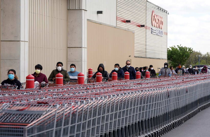 People wear masks as they wait to enter a Costco store during the outbreak of coronavirus in Washington (photo credit: REUTERS)