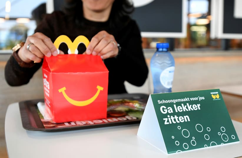 A customer receives her order inside a prototype location of fast food giant McDonald's for restaurants which respect the 1.5m social distancing measure, amid the coronavirus disease (COVID-19) outbreak, in Arnhem, Netherlands, May 1, 2020 (photo credit: REUTERS/PIROSCHKA VAN DE WOUW)