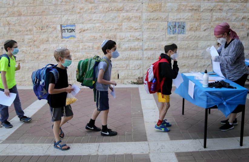 Israeli students at the Orot Etzion school in Efrat wear protective face masks as they return to school for the first time since the outbreak of the coronavirus, May 3, 2020 (photo credit: GERSHON ELINSON/FLASH90)