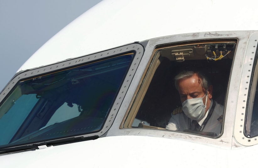A pilot wearing a protective mask is seen in a cargo aircraft chartered by the U.N. World Food Programme with medical supplies to help developing countries hit by the coronavirus disease (COVID-19) outbreak, at Liege airport, Belgium April 30, 2020. (photo credit: REUTERS)