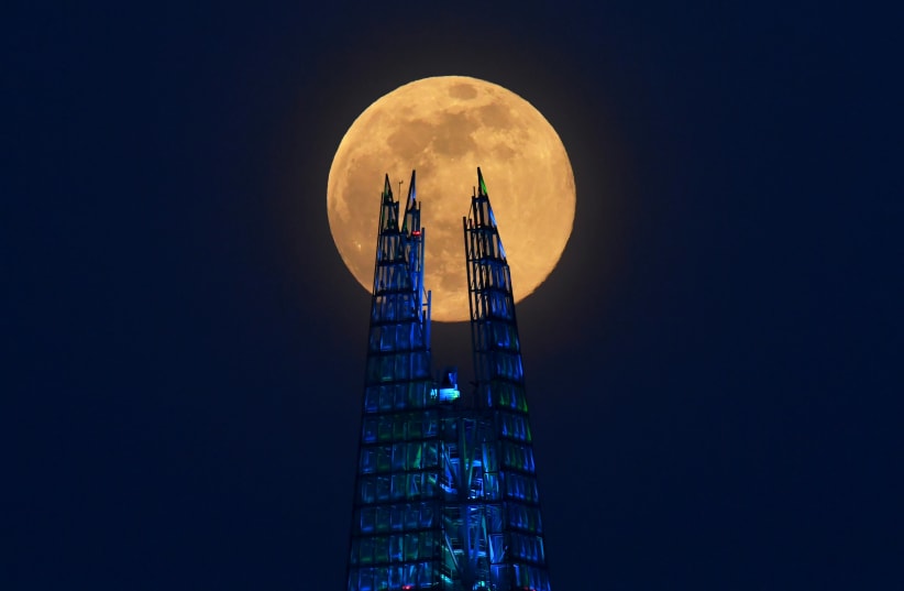 The pink supermoon rises over the Shard skyscraper in an astronomical event that occurs when the Moon is closest to the Earth in its orbit, making it appear much larger and brighter than usual, in London, Britain, April 7, 2020 (photo credit: REUTERS)