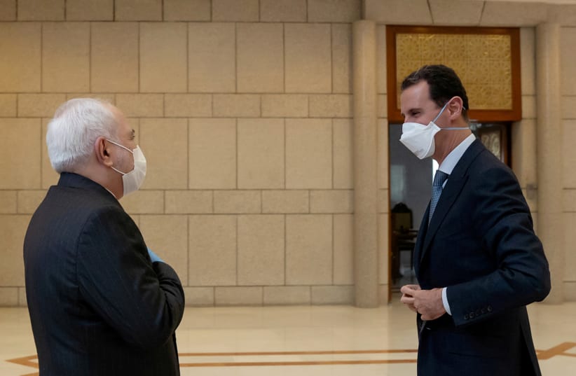 Syria's President Bashar al-Assad and Iran's Foreign Minister Mohammad Javad Zarif, wearing face masks as protection against the spread of the coronavirus disease (COVID-19), meet in Damascus, Syria, in this handout released by SANA on April 20, 2020 (photo credit: SANA/HANDOUT VIA REUTERS)