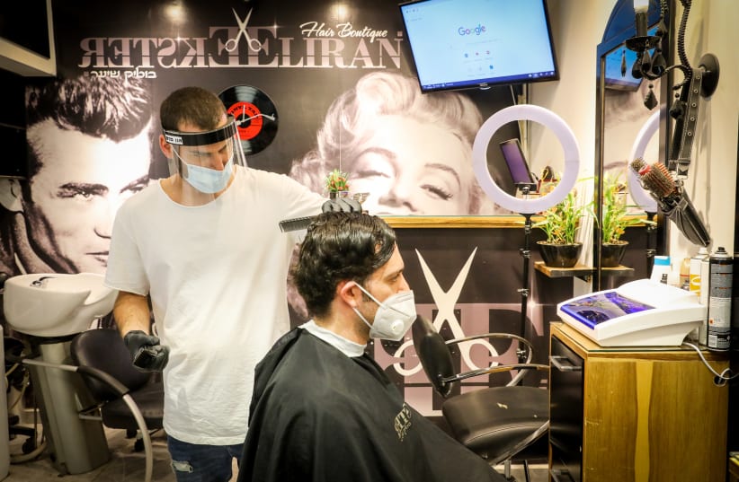A Jerusalem barber cuts the hair of a client wearing a mask (photo credit: MARC ISRAEL SELLEM)
