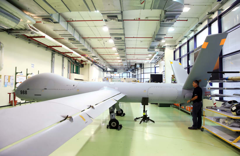 An employee stands next to an Elbit Systems Ltd. Hermes 900 unmanned aerial vehicle (UAV) at the company's drone factory in Rehovot, Israel (photo credit: REUTERS/OREL COHEN)