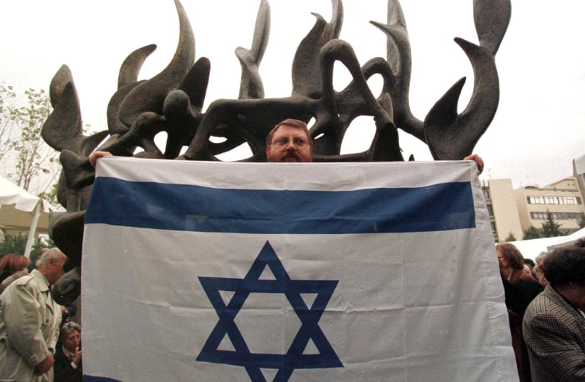 A Greek Jewish man holds an Israeli flag November 23 in front of a monument in memory of more than 50,000 Greek Jews murdered by Nazis during the Holocaust. (photo credit: REUTERS)