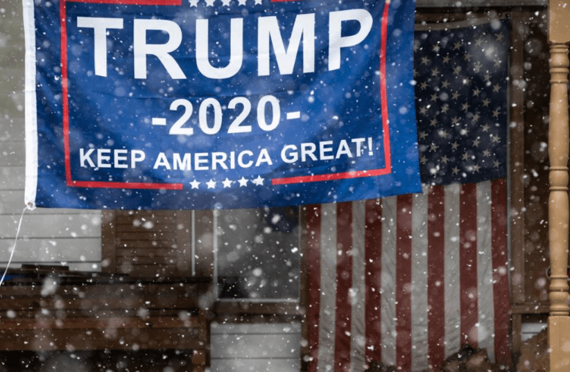 A Trump 2020 flag hangs on the front porch in a residential neighborhood in Livonia, Michigan, amid an outbreak of coronavirus disease, April 17, 2020. (photo credit: REUTERS)