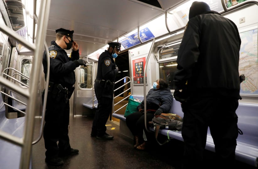 New York City Police Department (NYPD) officers remove a person from a carriage as the MTA Subway closed overnight for cleaning and disinfecting during the outbreak of the coronavirus disease (COVID-19) in the Brooklyn borough of New York City, U.S., May 7, 2020 (photo credit: REUTERS)