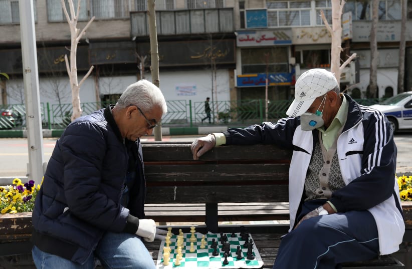 Men wear protective face masks and gloves, amid fear of coronavirus disease (COVID-19), play chess on the sidewalk of Mellat Park, in Tehran, Iran (photo credit: REUTERS)