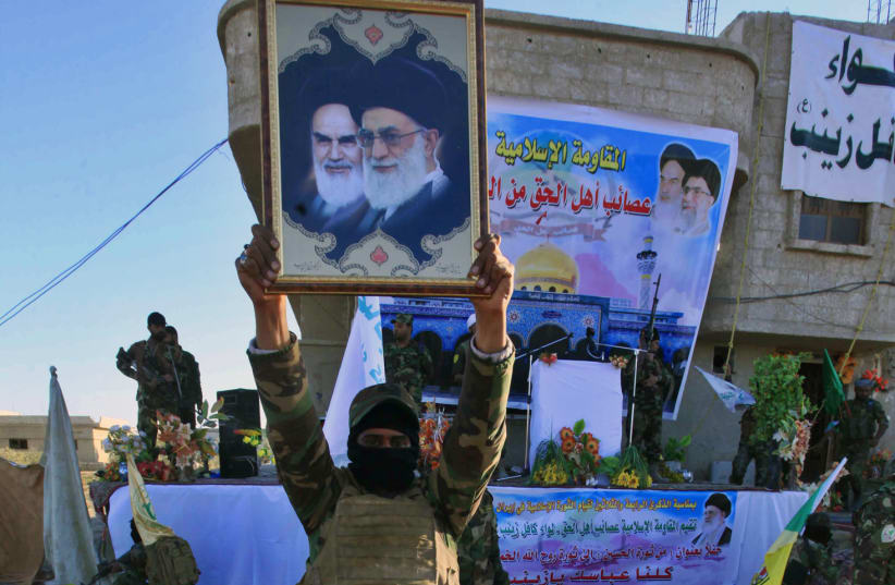 An Iraqi Shi'ite fighter holds a picture of Iran's Supreme Leader Ayatollah Ali Khamenei and cleric Ayatollah Khomeini during a military-style training at a camp on the outskirt of Damascus (photo credit: ALAA AL-MARJANI/REUTERS)