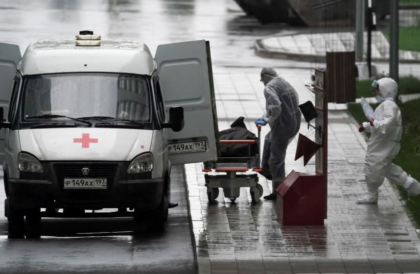 Medical specialists wearing protective gear push a stretcher while relocating a non-transparent bag, which presumably contains a human body, outside a hospital for patients infected with the coronavirus disease (COVID-19) on the outskirts of Moscow, Russia May 12, 2020 (photo credit: REUTERS/TATYANA MAKEYEVA)