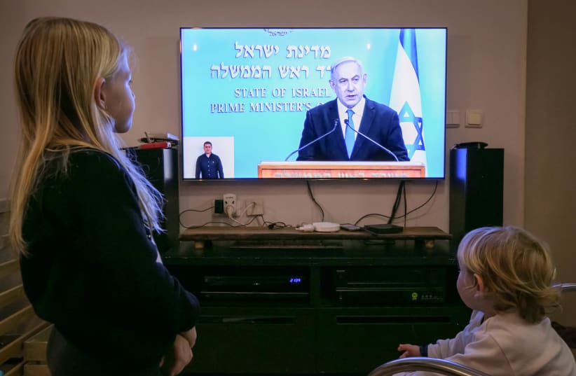 Israeli children watch as Israeli prime minister Benjamin Netanyahu holds a live press conference on the new government restrictions for the public regarding the coronavirus COVID-19 on March 19, 2020 (photo credit: CHEN LEOPOLD/FLASH90)