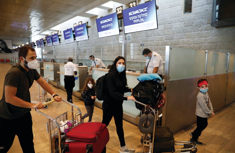 PASSENGERS WEARING masks push trolleys yesterday at the departures terminal at Ben-Gurion Airport. (photo credit: RONEN ZVULUN / REUTERS)