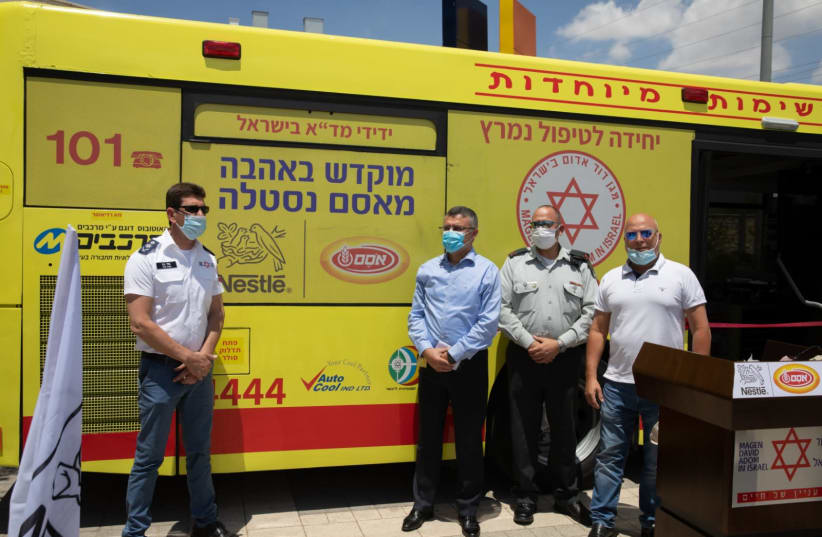 Magen David Adom staff and IDF officers standing in front of the newly built ambulance-bus (photo credit: Courtesy)