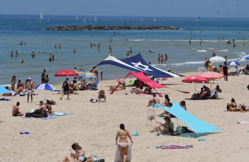 Beachgoers in Tel Aviv seek relief from the heatwave that hit the country (photo credit: AVSHALOM SASSONI/MAARIV)