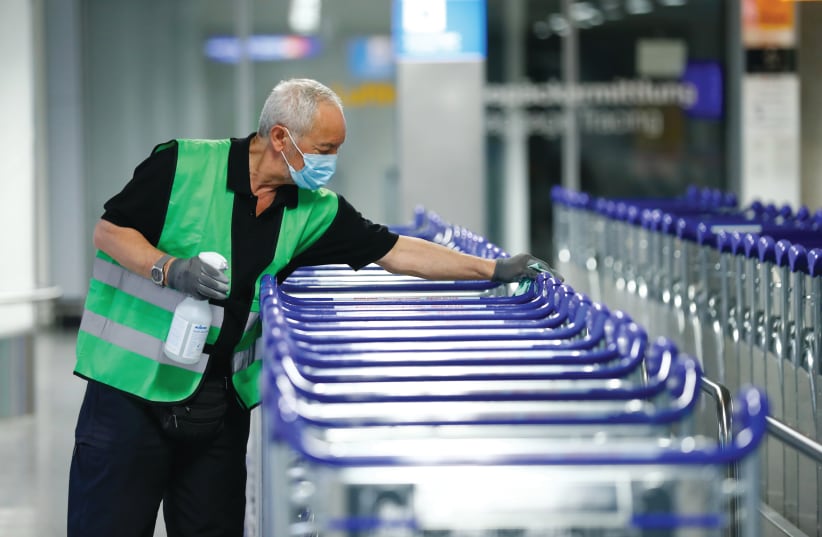 A WORKER disinfects baggage trolleys at Frankfurt Airport in Germany, last week (photo credit: REUTERS/RALPH ORLOWSKI)