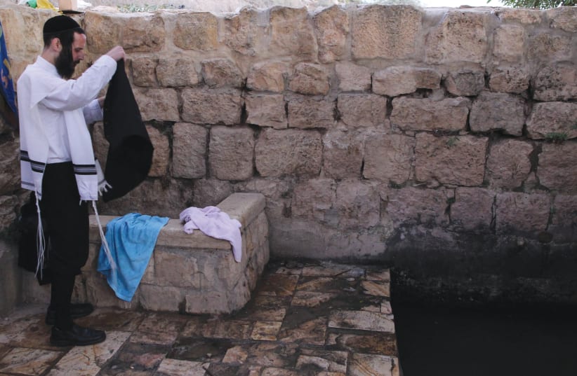 THE POWER of tzitzit: A haredi man gets dressed after immersing in a mikveh  near a water spring in Bat Ayin (photo credit: NATI SHOHAT/FLASH90)