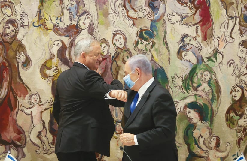 PRIME MINISTER Benjamin Netanyahu greets Blue and White leader Benny Gantz at the Knesset after the government was inaugurated on May 17 (photo credit: ALEX KOLOMOISKY / POOL)