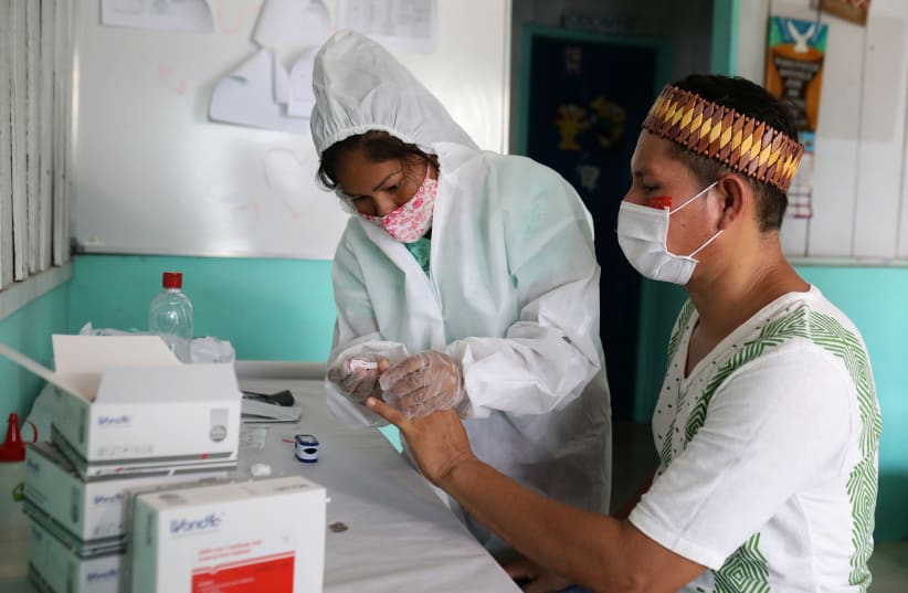 Kambeba indigenous nurse technician Neurilene Cruz, 36, conducts tests for the coronavirus disease (COVID-19) on indigenous Tome Cruz, 36, on the banks of the Negro river at the village of Tres Unidos, Amazon state, Brazil, May 21, 2020 (photo credit: BRUNO KELLY/REUTERS)