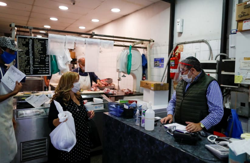 A BUTCHER SPEAKS with a customer at his kosher butcher shop in Buenos Aires, as Argentina works to organize the arrival of rabbis from Israel to keep kosher beef supply lines going in the midst of coronavirus restrictions on Wednesday (photo credit: REUTERS/AGUSTIN MARCARIAN)
