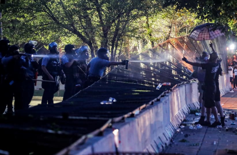 Riot police utilize pepper spray on protesters as demonstrations continue after a white police officer was caught on a bystander's video pressing his knee into the neck of African-American man George Floyd, who later died at a hospital, in Minneapolis, Minnesota, U.S., May 28, 2020. (photo credit: REUTERS/CARLOS BARRIA)