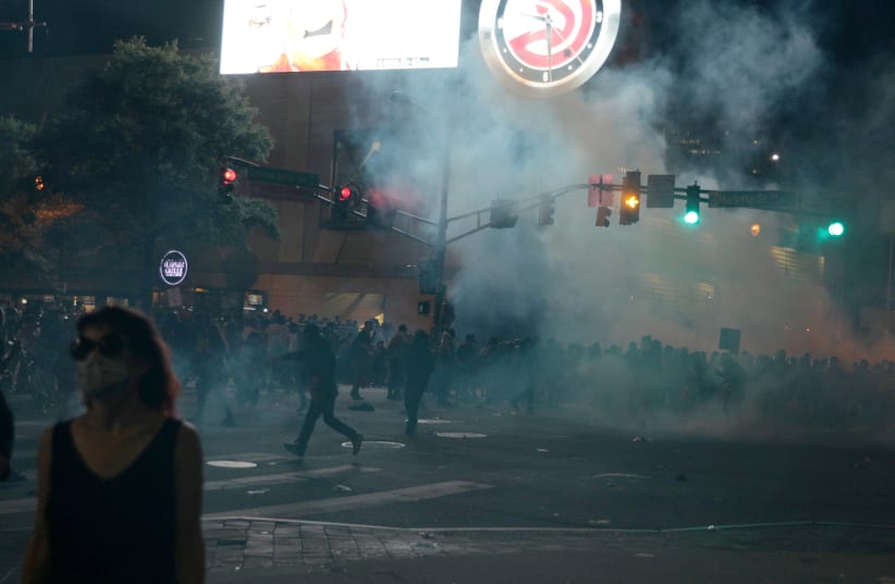 Protesters flee tear gas during a protest against the death in Minneapolis police custody of African-American man George Floyd, in Atlanta, Georgia, U.S. May 29, 2020.  (photo credit: REUTERS/DUSTIN CHAMBERS)