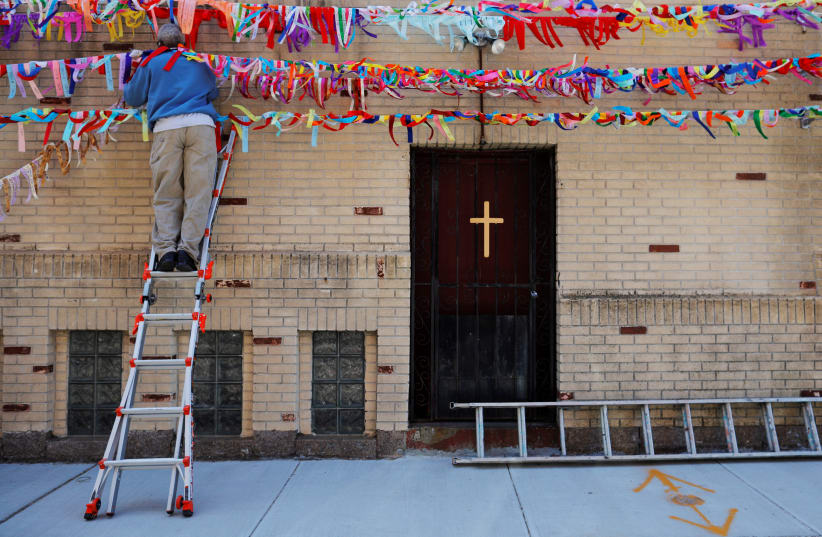 Frank Harris Jr. hangs the latest string of prayer ribbons for the over 6,000 Massachusetts residents who have died from the coronavirus disease (COVID-19) at Grant AME Church in Boston, Massachusetts, U.S., May 22, 2020 (photo credit: REUTERS/BRIAN SNYDER)