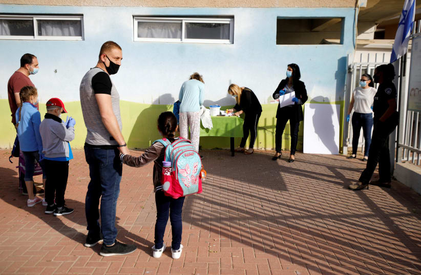 FILE PHOTO: Parents wait with their children to enter their elementary school in Sderot as it reopens following the ease of restrictions preventing the spread of the coronavirus disease (COVID-19) in Israel May 3, 2020 (photo credit: REUTERS/AMIR COHEN/FILE PHOTO)