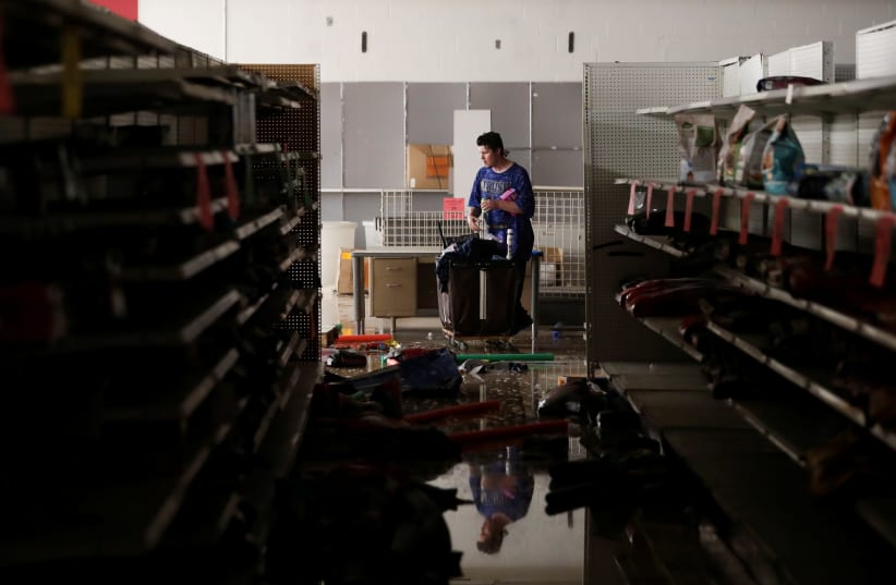 A man walks inside a damaged store as demonstrations against the death in Minneapolis police custody of George Floyd continue, in Minneapolis, Minnesota, U.S., May 30, 2020 (photo credit: LUCAS JACKSON / REUTERS)