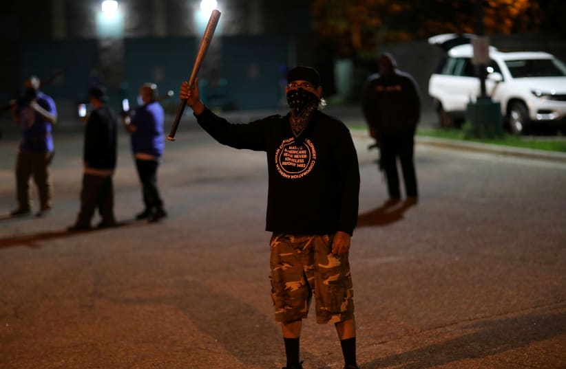 A man holds a baseball bat while protecting the premises of the Division of Indian Work, a non-governmental organization, as protesters continue to rally against the death in Minneapolis police custody of George Floyd, in Minneapolis, Minnesota, U.S. May 30, 2020 (photo credit: REUTERS/LEAH MILLIS)
