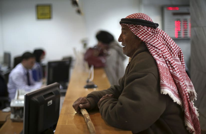 A Palestinian man waits at a counter to make a withdrawal at the Housing Bank for Trade & Finance in the West Bank city of Ramallah January 22, 2013 (photo credit: MOHAMAD TOROKMAN/REUTERS)
