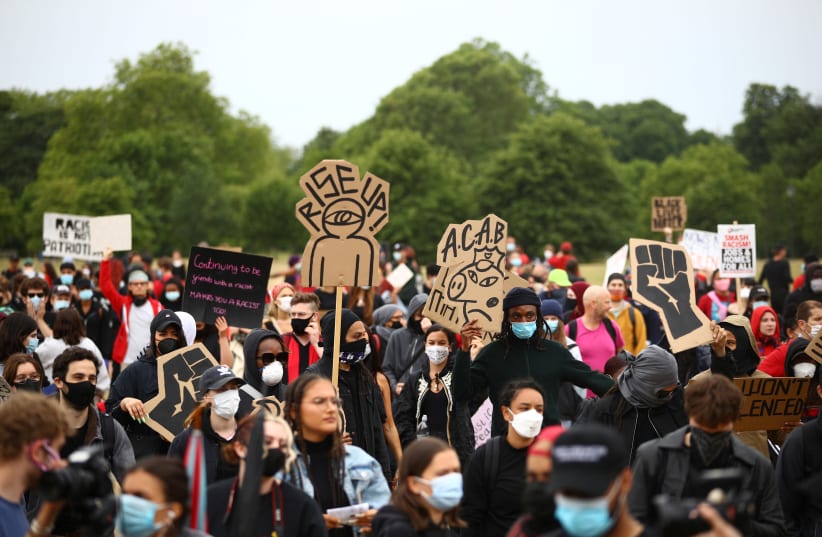 People wearing face masks hold banners in Hyde Park during a "Black Lives Matter" protest following the death of George Floyd who died in police custody in Minneapolis, London, Britain, June 3, 2020. (photo credit: REUTERS / HANNAH MCKAY)