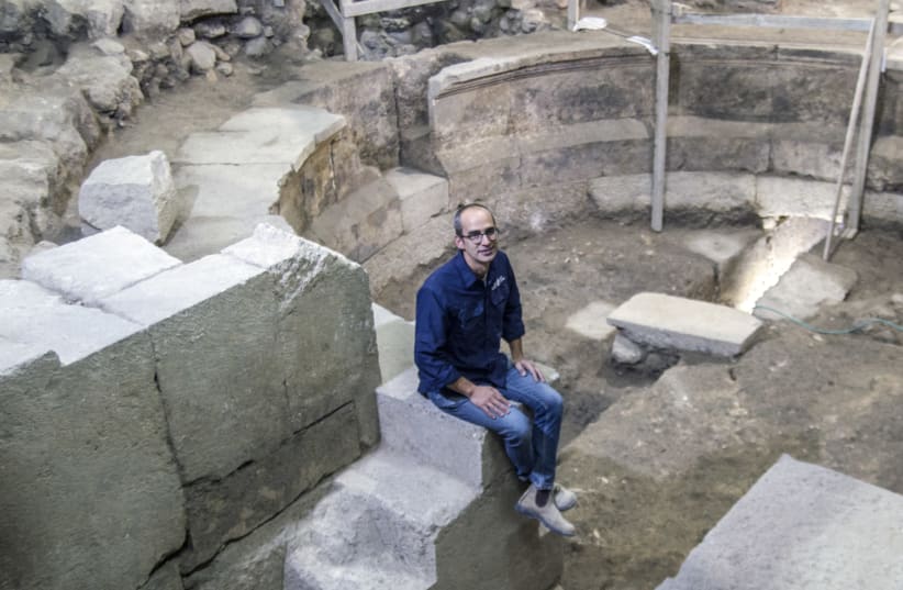 Dr. Joe Uziel of the Israel Antiquities Authority sits on the steps of the theater-shaped building uncovered in the area of Wilson's Arch by the Western Wall.  (photo credit: YANIV BERMAN/IAA)