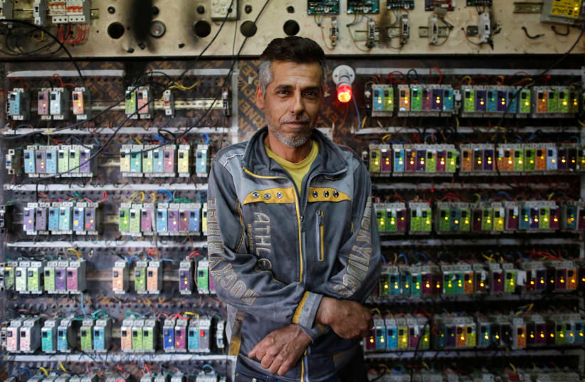 An Iraqi technician poses in front of an electric switchboard at a private generator workshop, in eastern Mosul (photo credit: REUTERS)