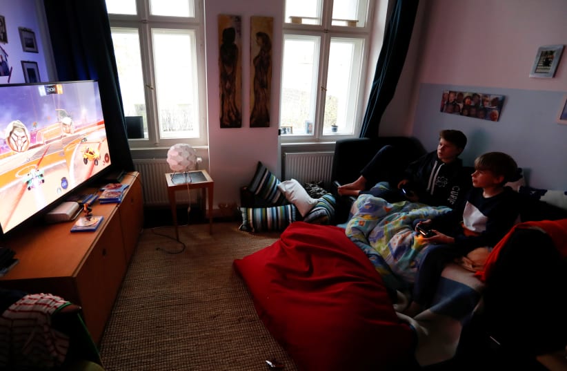 Malte and Rasmus Bruhn play a video game after dinner at home as the spread of the coronavirus disease (COVID-19) continues in Berlin. (photo credit: REUTERS)