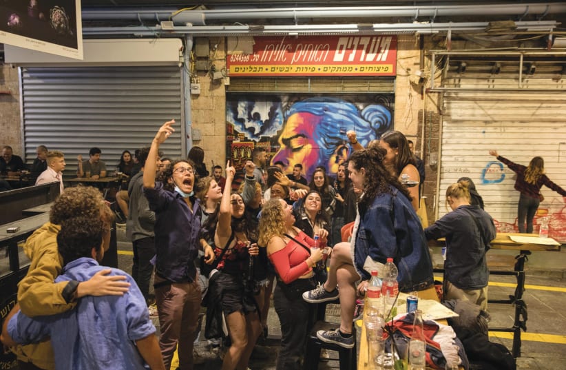 JOYOUS, LARGELY maskless patrons dance at a bar in Jerusalem’s shuk, as eateries and nightlife spots reopened on May 27 (photo credit: OLIVIER FITOUSSI/FLASH90)