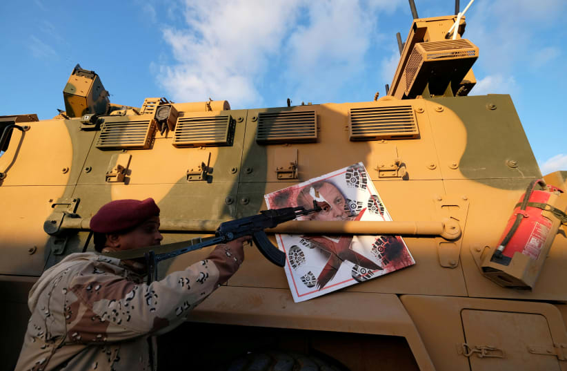 A MEMBER of Libyan National Army (LNA) commanded by Khalifa Haftar, points his gun to the image of Turkish President Tayyip Erdogan hanged on a Turkish military armored vehicle, which LNA said they confiscated during Tripoli clashes, in Benghaz (photo credit: REUTERS)