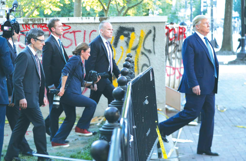 US PRESIDENT Donald Trump walks past a building defaced with graffiti by protesters in Lafayette Park. June 1, 2020.  (photo credit: REUTERS//TOM BRENNER)