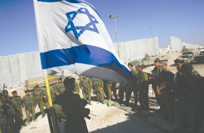 IDF SOLDIERS take part in a flag-lowering ceremony as they prepare to withdraw from Girit outpost, in the southern Gaza Strip, in 2005. (photo credit: DAVID SILVERMAN / REUTERS)