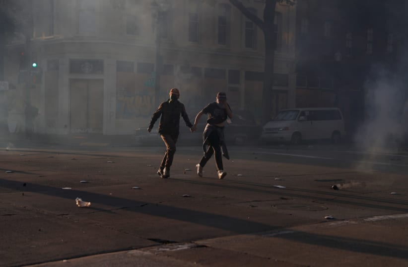 Demonstrators run from tear gas during a rally amid nationwide unrest following the death in Minneapolis police custody of George Floyd, in Oakland, California, U.S., June 1, 2020 (photo credit: STEPHEN LAM / REUTERS)