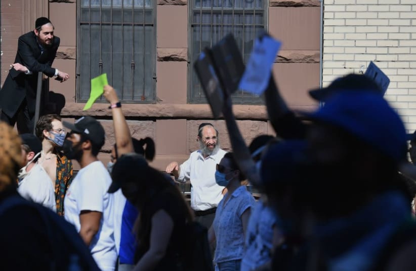 Members of the Orthodox Jewish community watch as protesters walk through the Brooklyn borough on June 3, 2020 (photo credit: ANGELA WEISS/AFP VIA GETTY IMAGES/JTA)