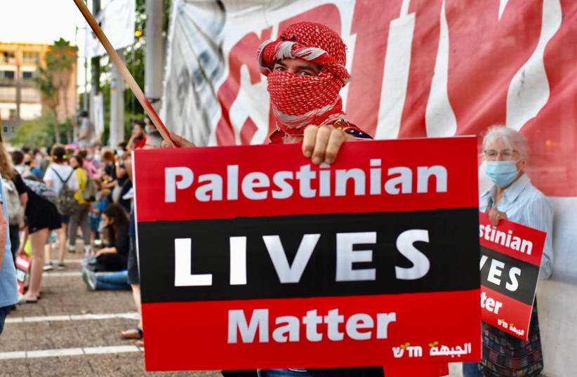 A Palestinian holds a poster reading, "Palestinian Lives Matter" at an anti-annexation protest in Tel Aviv. (photo credit: AVSHALOM SASSONI)