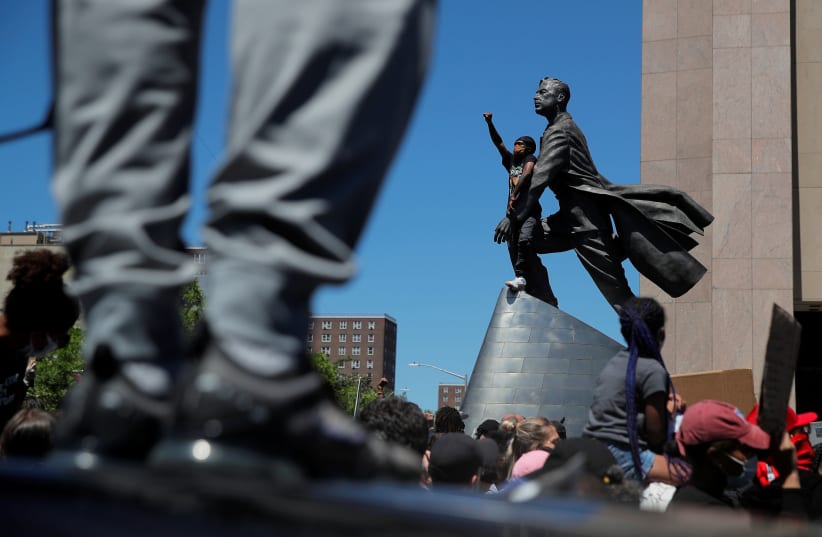 A protester gestures near the statue of Adam Clayton Powell Jr as people rally against the death in Minneapolis police custody of African-American George Floyd, in Manhattan, New York, U.S. (photo credit: REUTERS)