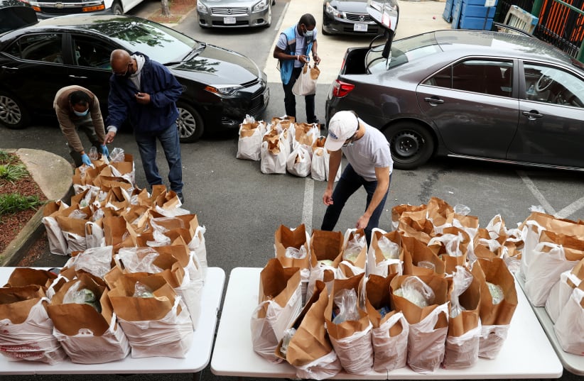 Contract drivers paid by Amazon collect bags of free groceries to deliver from the Bread for the City social services charity during the coronavirus disease (COVID-19) outbreak, in Washington (photo credit: JONATHAN ERNST / REUTERS)