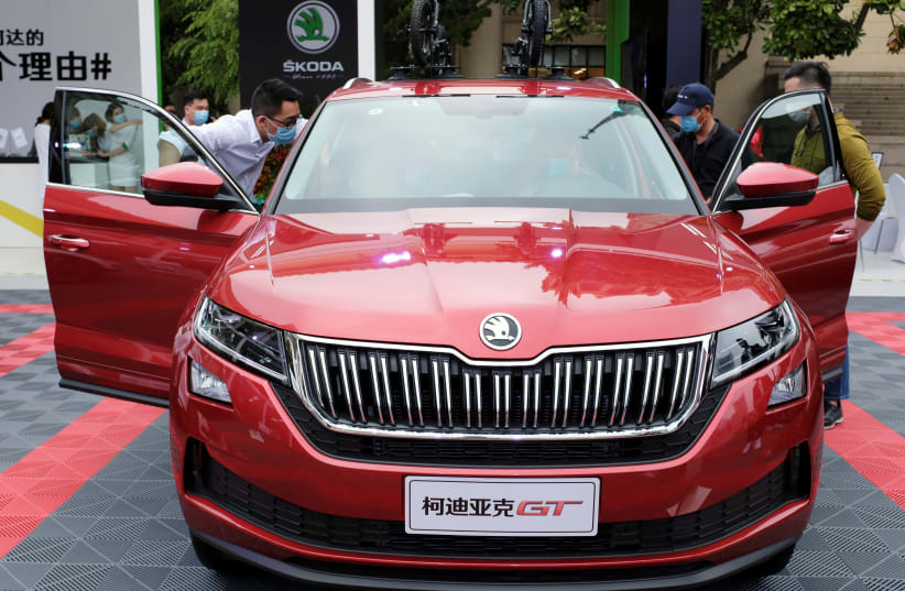 Visitors wearing face masks following the coronavirus disease (COVID-19) outbreak check a Skoda vehicle at a sales event in Shanghai, China May 5, 2020. (photo credit: REUTERS)